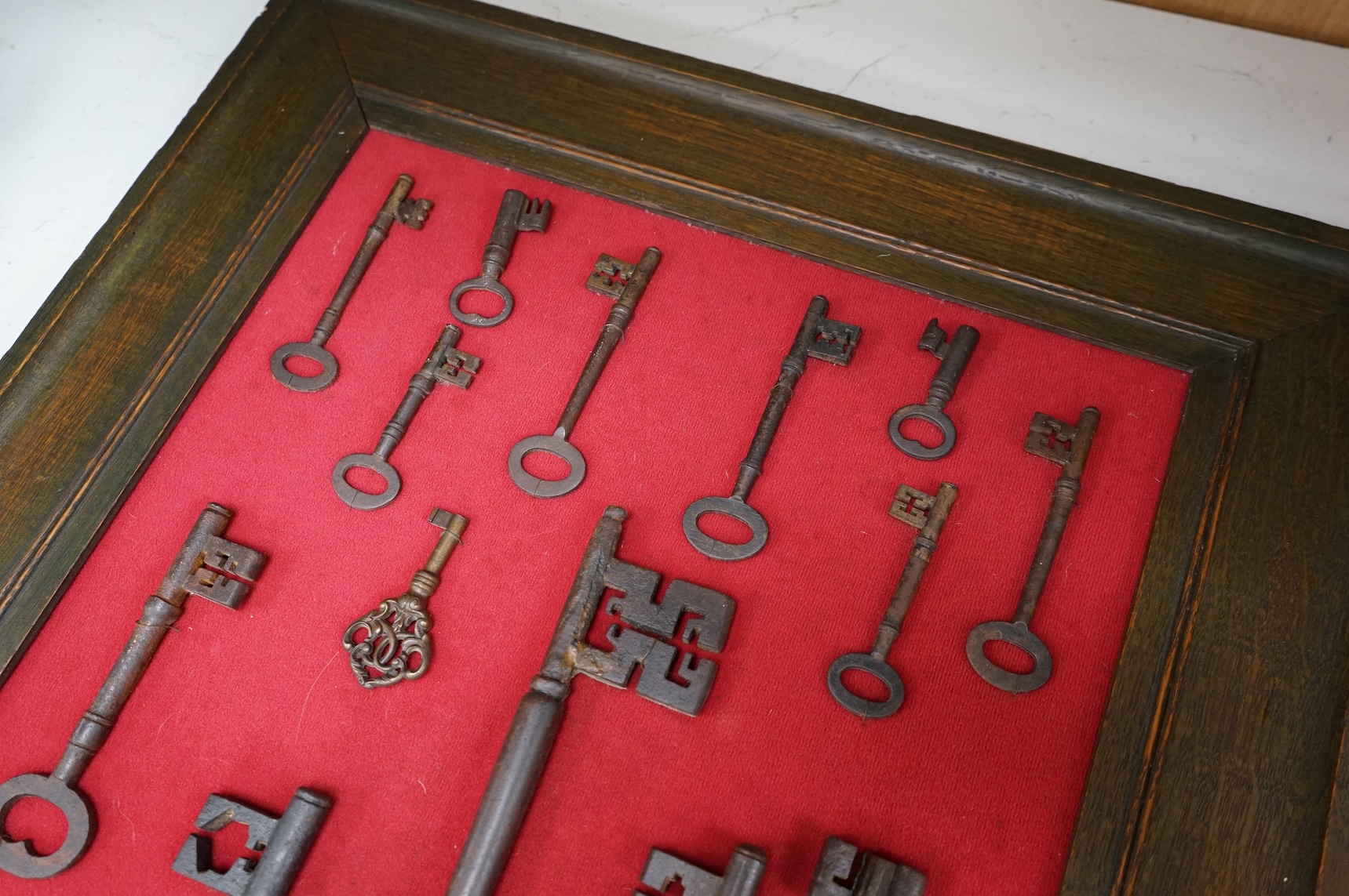 A framed collection of early antique iron keys, largest key 25cm long, board with all keys 66cm high